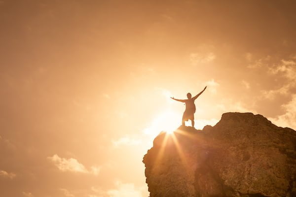 Man on top a mountain celebrating. Victory and success concept.